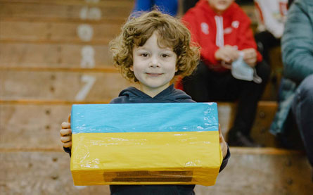 Chłopiec niosący paczkę w kolorach ukraińskiej flagi